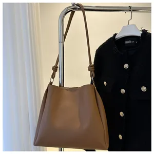 Détail d'un sac cabas en cuir marron avec bandoulière nouée et anneaux métalliques