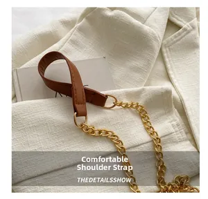 Detail of a brown leather and gold chain shoulder strap on a quilted crossbody bag
