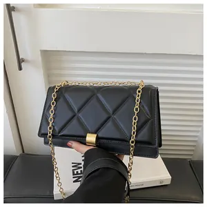 Close-up of black quilted leather with gold chain strap and square metal buckle