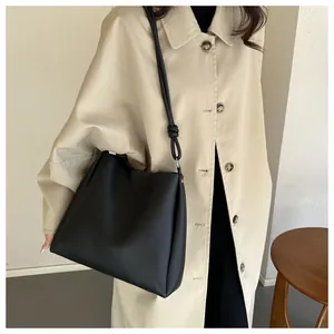 Détail du grand sac cabas noir avec bandoulière nouée unique et anneaux métalliques argentés