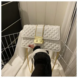 Close-up of quilted white leather crossbody bag with gold metal lock and chain strap