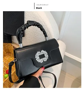 Detail of black handbag showing sparkling crystal flower clasp and scrunchie handle