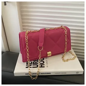 Detailed close-up of rose red quilted crossbody bag with golden chain and metallic buckle