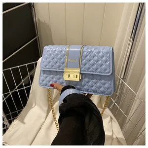 Detail of light blue quilted crossbody bag with gold fashion buckle and chain strap