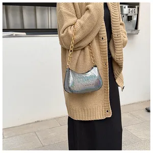 Close-up of glittery silver half-moon bag featuring a thick gold metallic chain strap