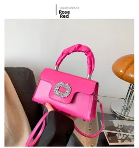 Close-up of rose red handbag featuring sparkling square rhinestone buckle and ruffled handle