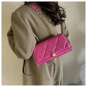 Close-up of fuchsia quilted leather chain bag worn with a beige wool coat