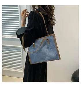 Detail of blue marble pattern tote bag with brown leather straps and gold rivets