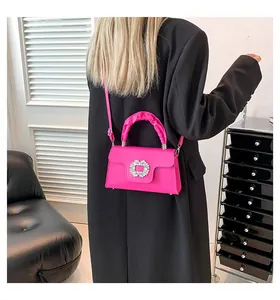Detail of rose red handbag with rhinestone buckle and ruched handle on black suit