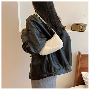 Close-up of white glitter underarm bag with gold chain strap worn on black leather jacket