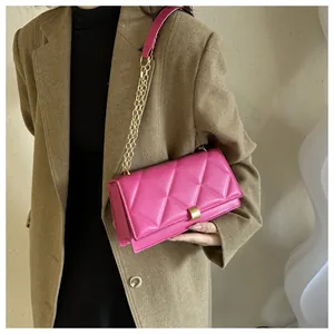 Detail of fuchsia quilted chain bag with gold rectangular buckle and leather strap