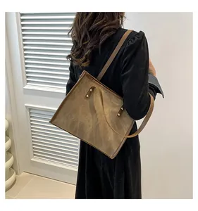 Detail of vintage brown suede tote bag with slim shoulder straps and gold metal rivets