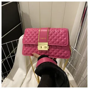 Close-up of pink quilted crossbody bag with gold chain and fashion lettering metal buckle