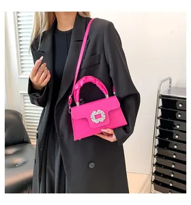 Detail of a hot pink crossbody bag with a sparkling square rhinestone buckle and ruched handle