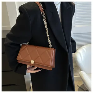 Detail of brown quilted faux leather bag with gold metal lock and chain strap
