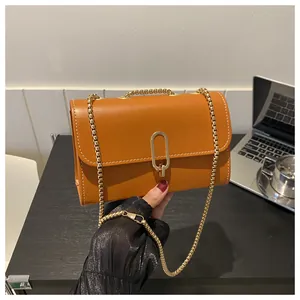 Detail of orange small square bag with gold oval buckle and fine white stitching