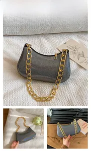 Close-up of black shoulder bag featuring shimmering fabric and a chunky gold chain strap