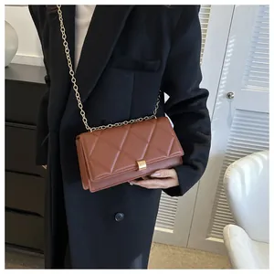 Detail of brown quilted leather bag featuring gold metal chain and rectangular buckle