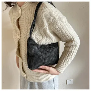 Nahaufnahme einer funkelnden schwarzen Strass-Tasche an einem Modell im Strickpullover