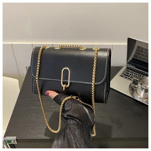 Detail of black mini crossbody bag featuring white stitching and gold oval lock