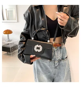 Detail of elegant black leather handbag featuring crystal square buckle and ruched handle