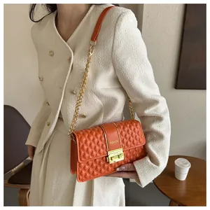 Orange quilted shoulder bag with gold chain strap worn by a model in a modern interior