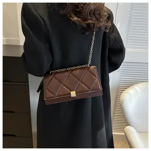 Close-up of a brown quilted crossbody bag with a gold chain strap and metal clasp