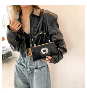 Detail of black leather handbag with sparkling rhinestone square buckle and ruched handle