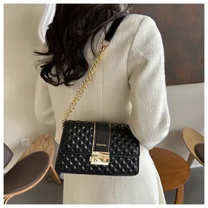 Detail of a quilted black crossbody bag with gold chain and "FASHION" text strap