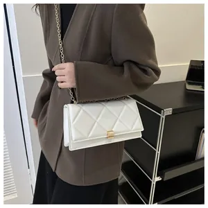 Close-up of quilted pattern and gold metal lock on white crossbody chain bag