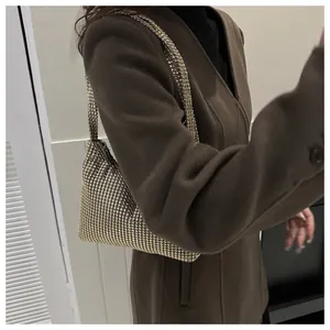 Detailansicht der goldenen Strass-Schultertasche mit Kette über einem braunen Mantel