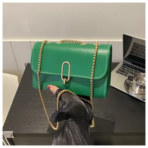 Close-up of green square crossbody bag featuring gold chain and white contrast stitching