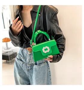 Detail of green leather handbag featuring a crystal buckle and ruffled handle