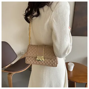 Detail of quilted diamond pattern and golden chain strap on a beige crossbody bag