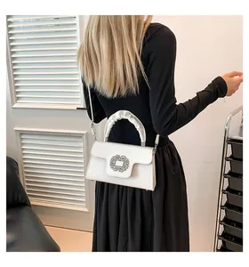 Detail of white leather shoulder bag with crystal buckle and pleated handle on model