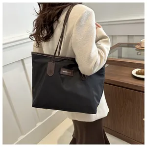 Detail of black oxford tote bag with dark brown straps shown in a lifestyle indoor setting