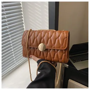 Detailansicht braune Stepptasche mit goldenem Verschluss und Kettenriemen-Struktur