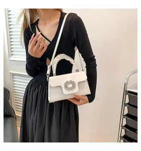 Detail of white square handbag featuring a sparkling rhinestone buckle and ruched handle