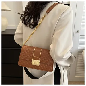 Detailed macro view of brown quilted crossbody bag featuring gold chain and FASHION logo