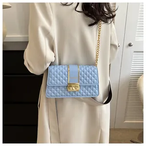 Detail view of light blue quilted crossbody bag with gold chain strap on shoulder