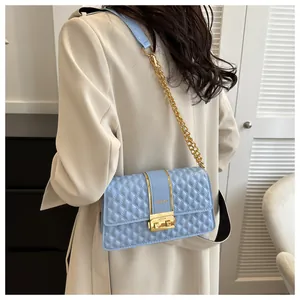 Detail of light blue quilted crossbody bag with gold FASHION lock and chain strap