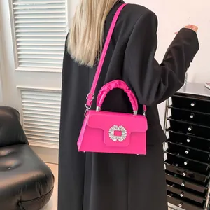 Magenta satchel with crystal buckle and ruched handle, worn as a crossbody bag
