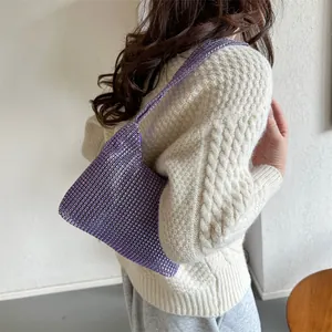 Schicke lila Handtasche mit Strasssteinen und Kette, am Model im Strickpullover gezeigt