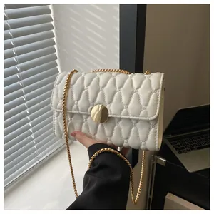 Detailansicht der weißen Stepptasche mit goldener Rundschnalle und Gliederkette