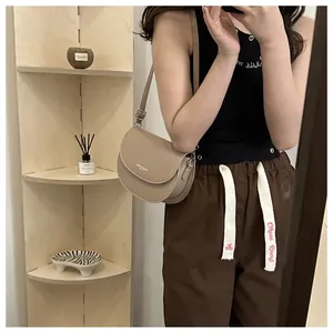 Détail d'un sac besace beige minimaliste avec bandoulière réglable et logo de la marque