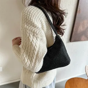 Modische schwarze Strass-Hobotasche, von einem Model über einem Strickpullover getragen