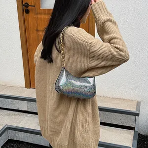 Chic silver glitter underarm bag with gold chain strap shown on a model