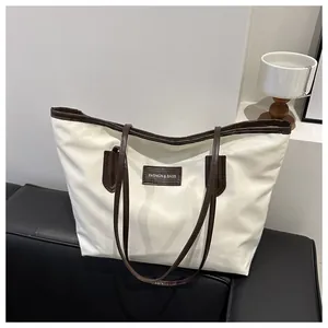 Detail view of large Oxford cloth tote bag with brown leather trim and fashion patch