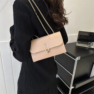Minimalist beige crossbody bag with gold chain strap shown in an office setting