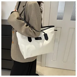 Close-up of a large black and white color-block Oxford cloth tote bag worn by a model